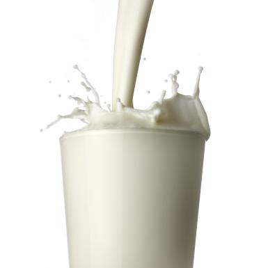 Milk being poured into glass, white background